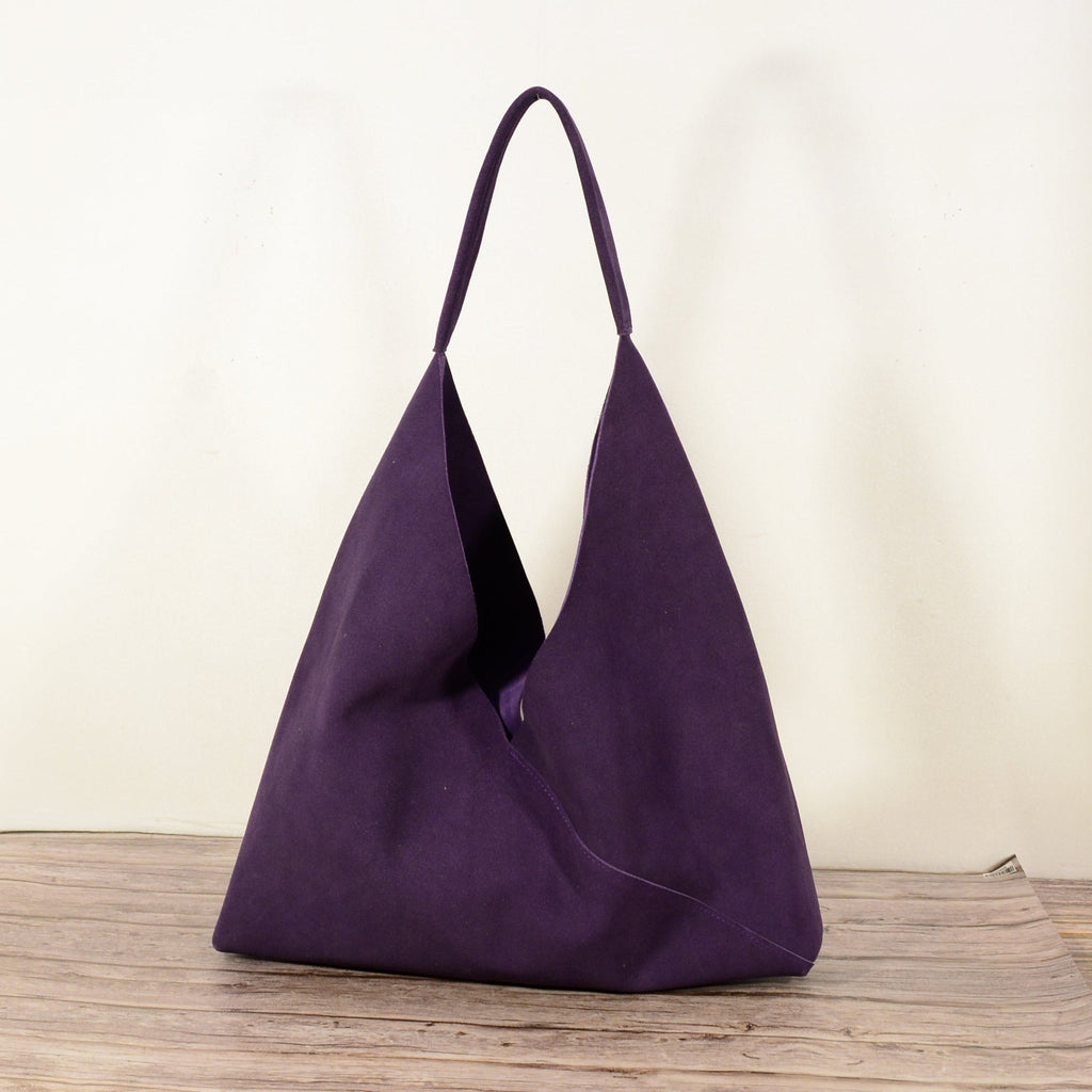 Purple suede hobo shoulder bag studio shot on wooden surface