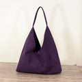 Purple suede hobo shoulder bag studio shot on wooden surface