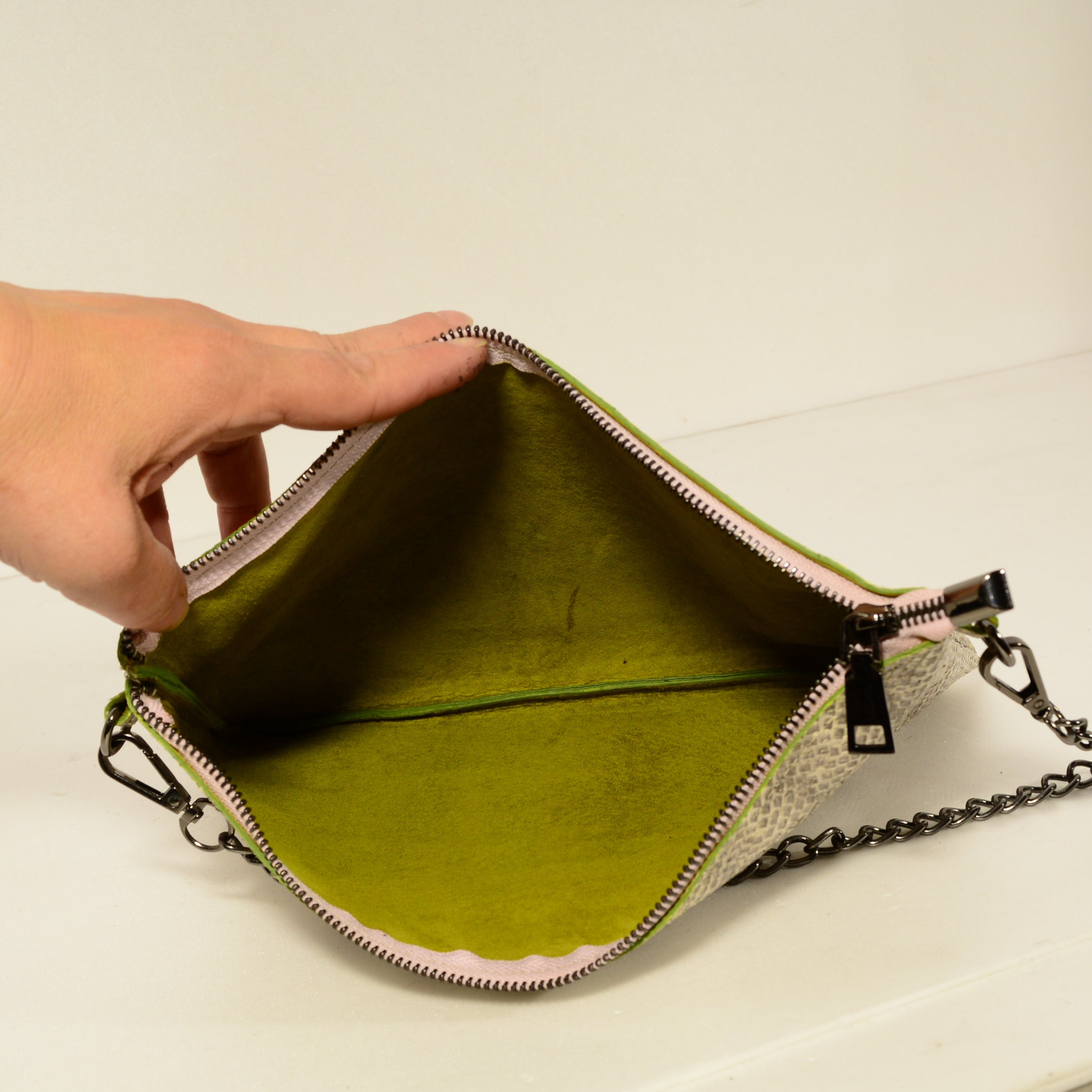 Snake print leather bag open showing vibrant lime-green lining interior